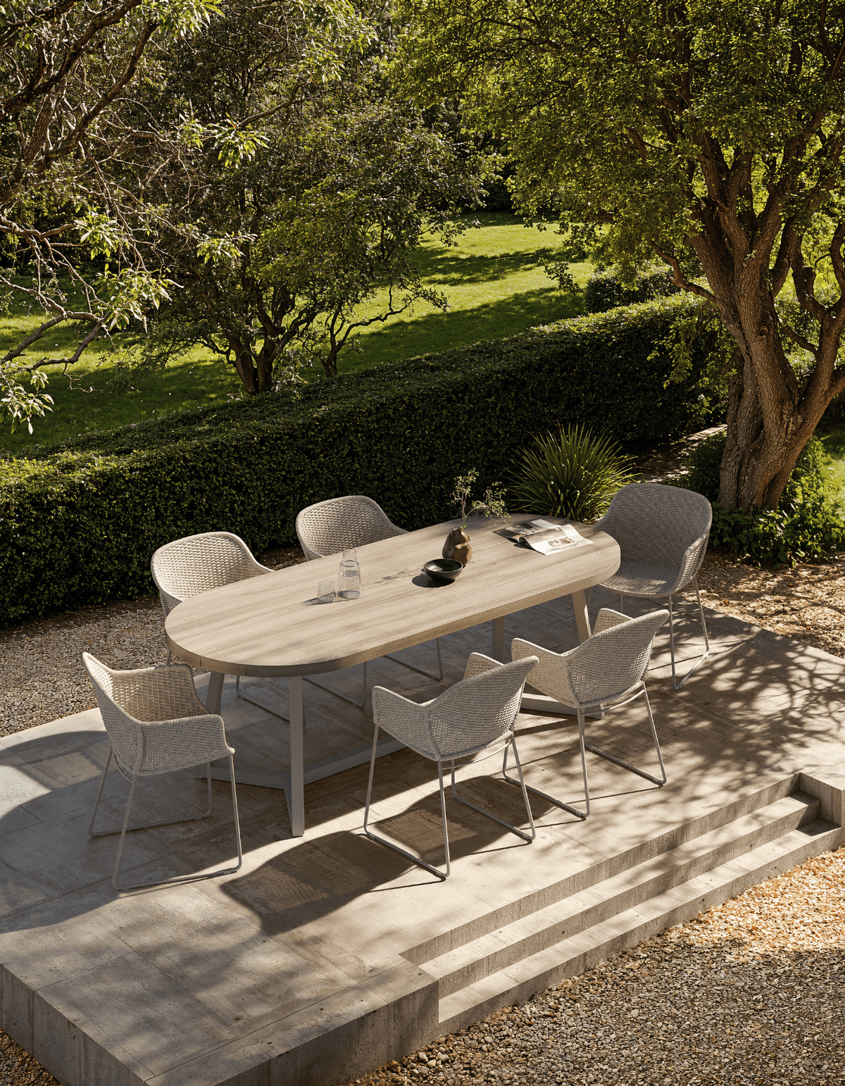 Clareville Dining Chairs around an oval dining table on a stone terrace in a garden