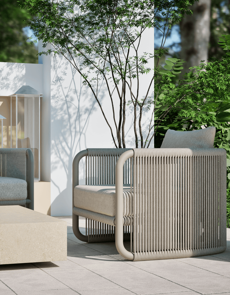 Capri Lounge Chair in Dove Grey in a courtyard with a white wall and tree