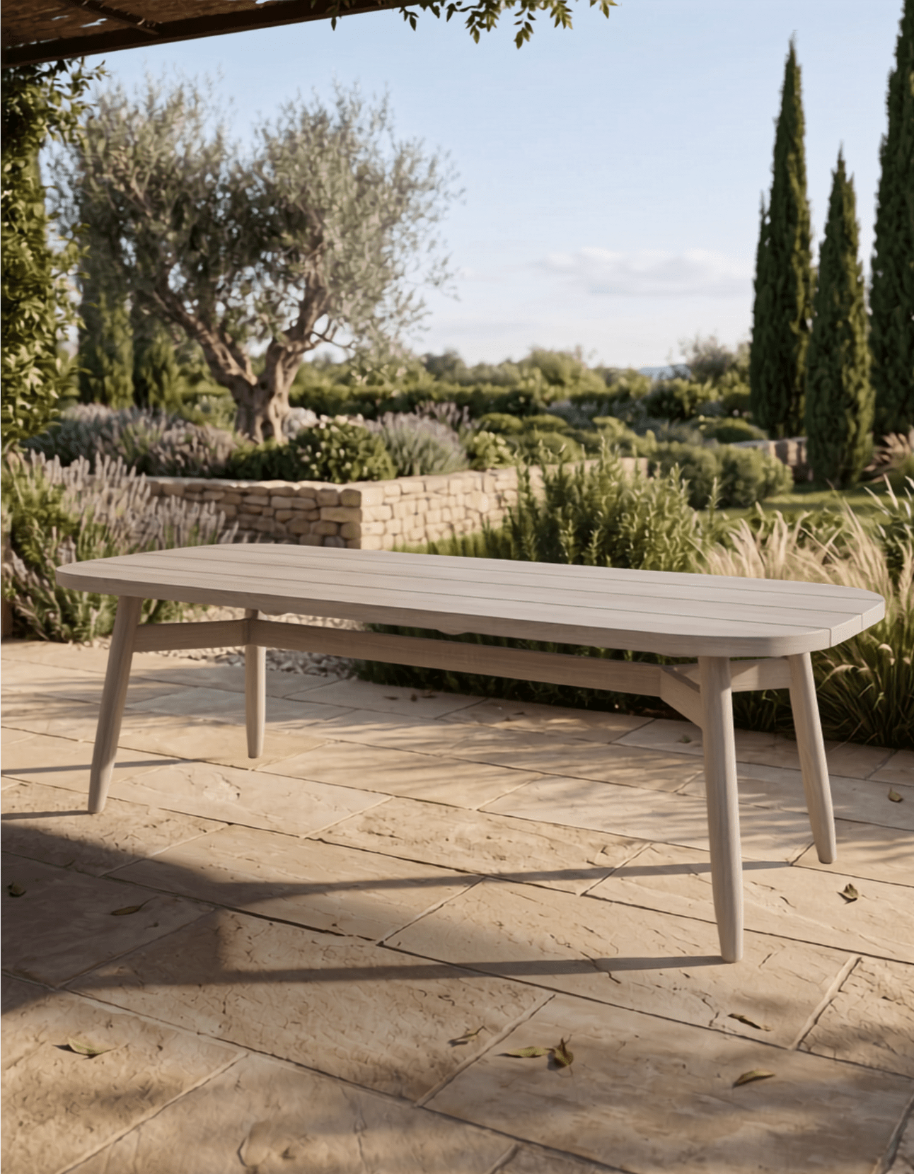 Wooden outdoor table on a stone patio with garden and trees in the background