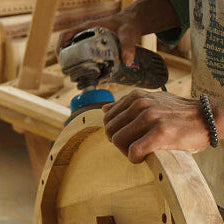 Person using a power tool on wooden furniture in a workshop setting