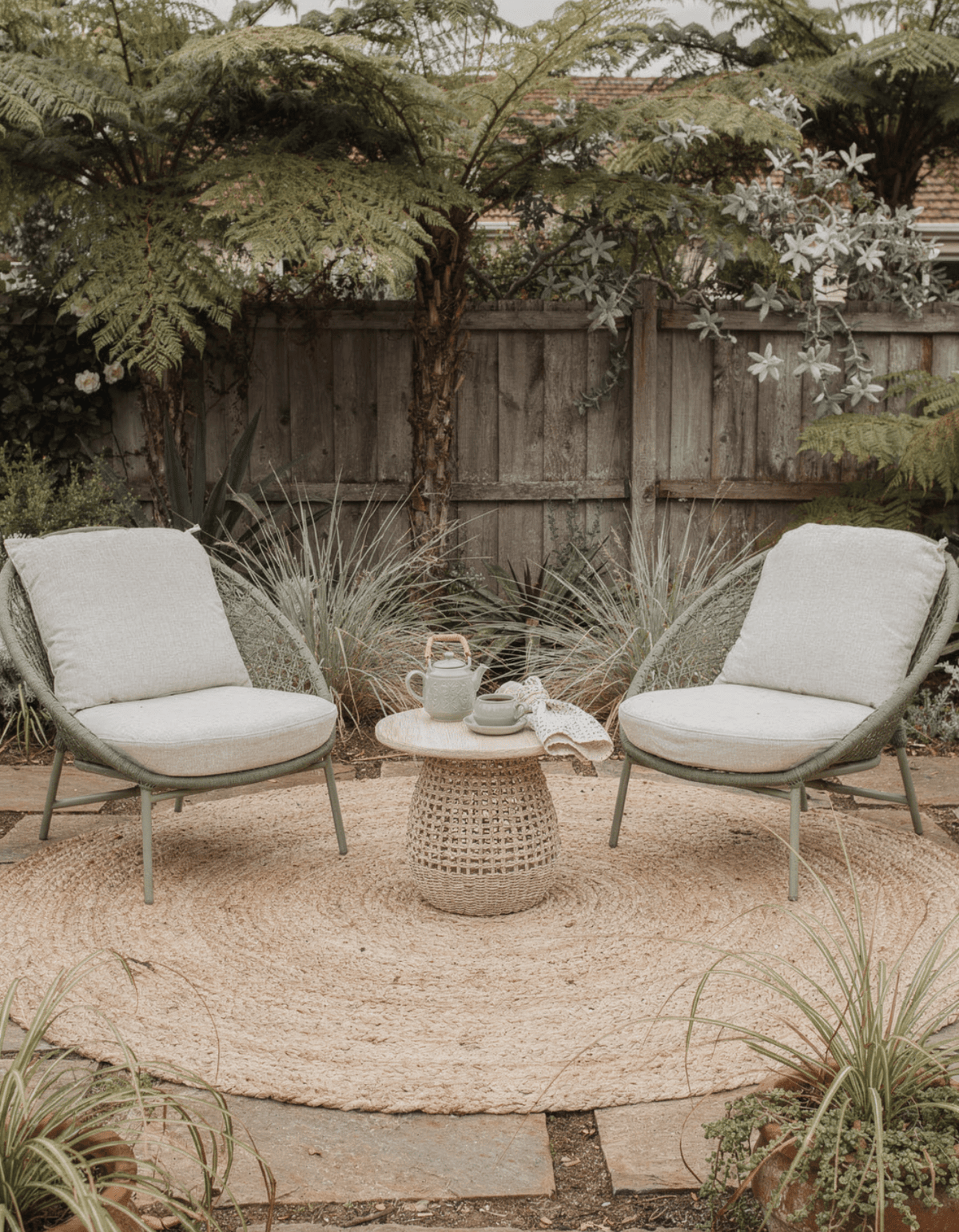 Two Ningaloo Lounge Chairs with a woven side table in a gravel garden courtyard